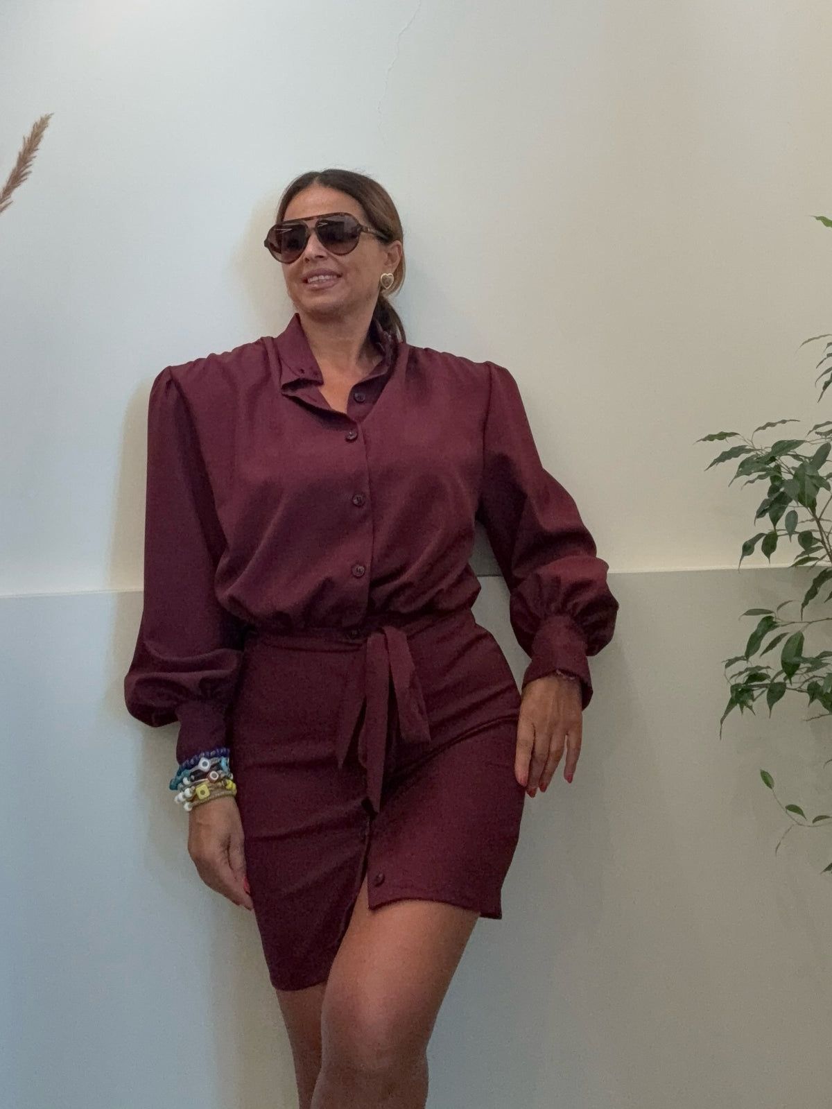 Modella indossa un abito chemisier bordeaux Amuleto® Fashion Store con maniche a palloncino e cintura in vita